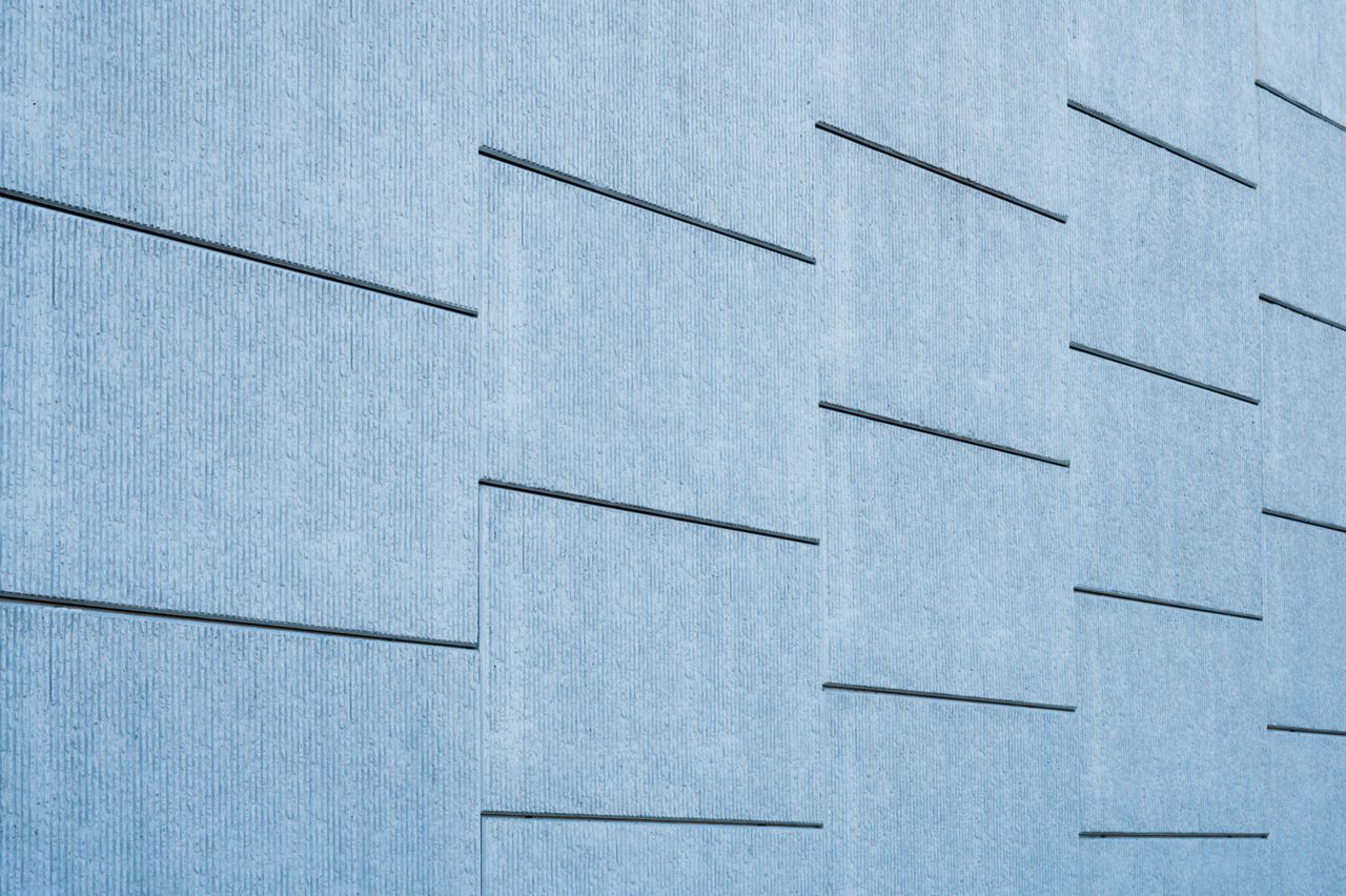 Strona główna Blue tinted concrete wall featuring sleek geometric lines and modern architecture.